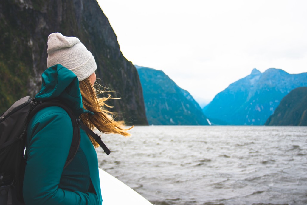 nominated-woman-enjoying-the-beautiful-scenery-of-the-milford-sound-in-new-zealand-while-looking-out_t20_mopJyl